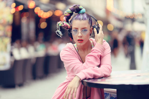 Young woman listening to music via headphones on the street - Hipster Girl with a nonconformist fashion look stock photo