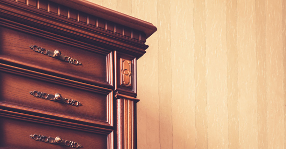 vintage dark brown chest of drawers corner with delicate bronze handles and luxurious golden stripe extreme close view