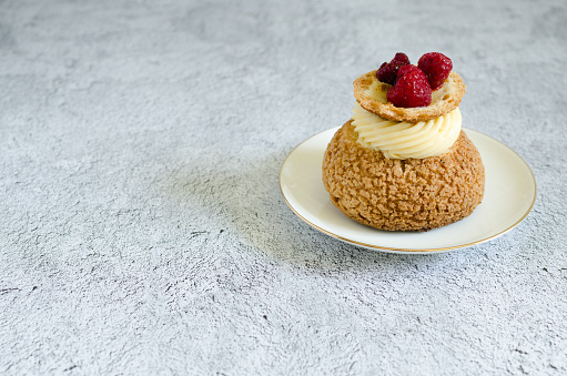 Homemade choux pastry shu with raspberry confit and lime cream on a plate