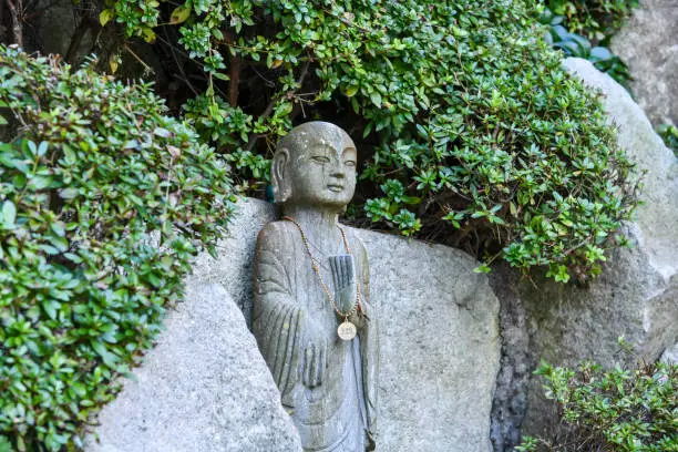 Buddhist statue peeking out of a bush. Haedong Yonggung Temple, in Gijang-gun, Busan, South Korea.