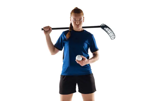 Floorball female player isolated on white studio background. Action and motion, movement, healthy lifestyle and overcoming concept. Young caucasian woman in sportwear training, practicing the game.