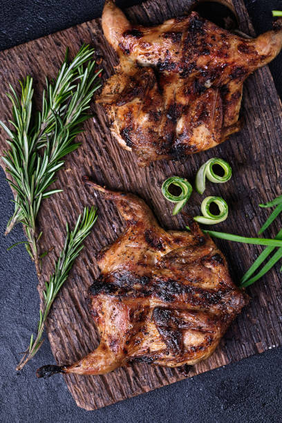 istock Two grilled quail served on a cutting board on a dark background 1223608366