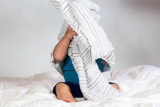 istock Caucasian Toddler playing under a striped blanket on white duvet bedding 1223610070