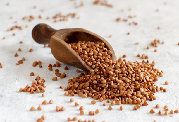 istock Raw dry buckwheat grain with a spoon on a white table 1223614199