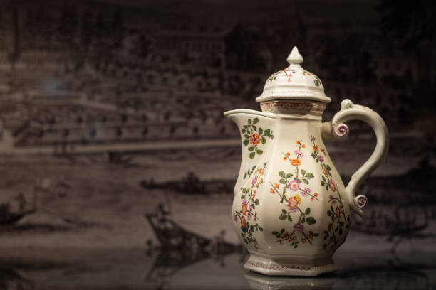 Closeup of a beautiful old coffee pot made of porcelain, painted with flowers standing on a reflective table