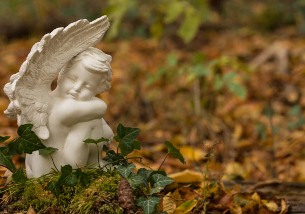 White cherub or angel, nature cemetery in the forest