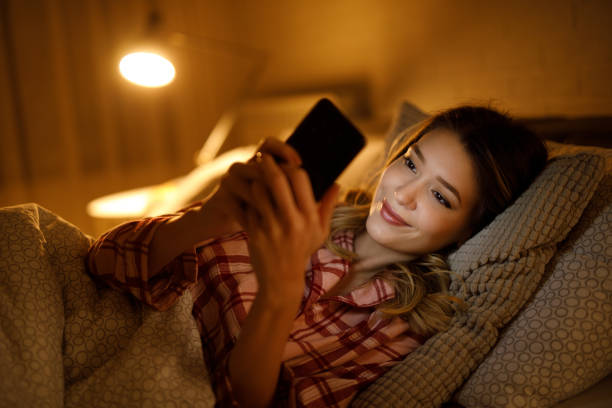 istock Beautiful young woman using mobile phone in bed at night 1223618811