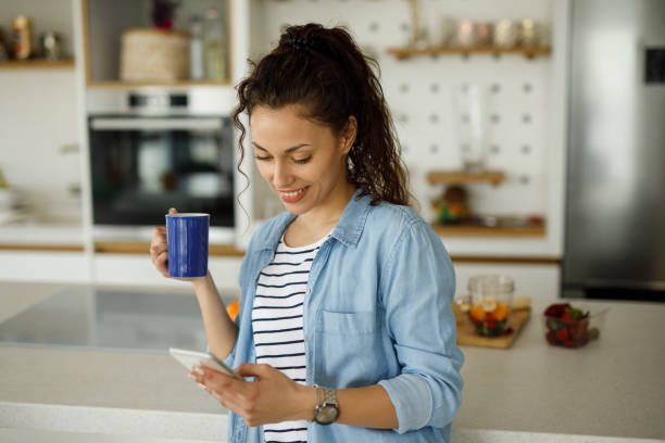 istock Young woman drinking first morning coffee and using smart phone 1223620270