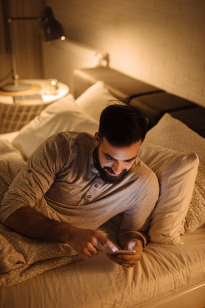 istock Handsome bearded man using phone in the bed at night 1223620458