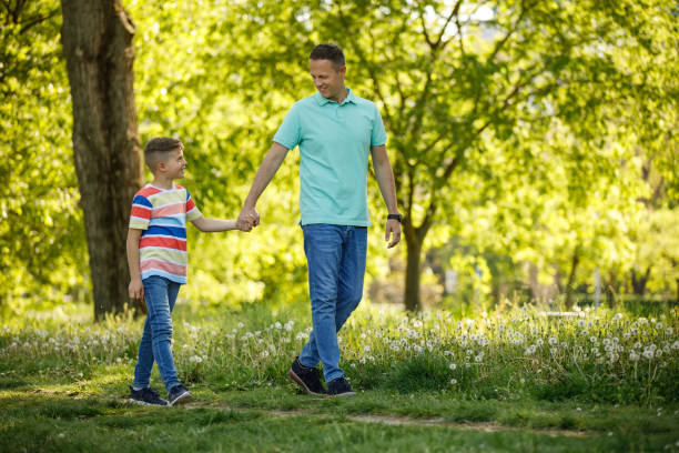 istock Father and son holding hands and walking through park 1223621074