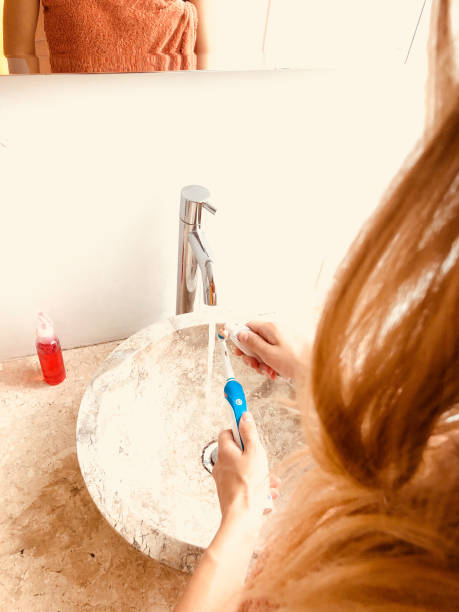 istock Woman using toothbrush in a bright lit bathroom. 1223623034