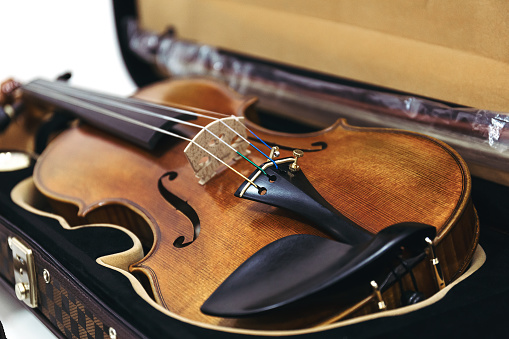 A violin in a dark open case. Classic stringed musical instrument. Selective focus. Close up.