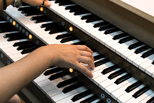 Close- up of a woman's hands playing a three-manual electronic organ.