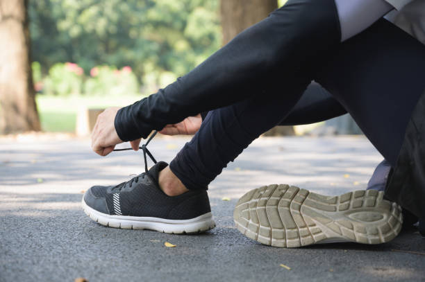 ランニングシューズに靴ひもを結ぶアスリートの男性の手 - jogging group of people park running ストックフォトと画像