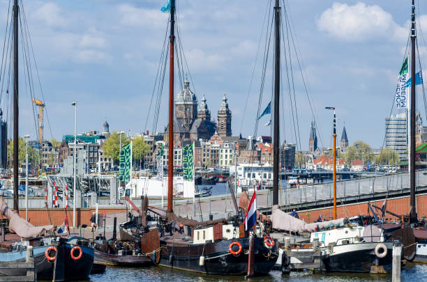 Boats moored in the harbor on the Amstel River with St. Nicholas Basilica in the distance