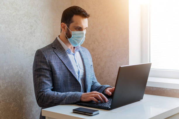 istock A man in a medical mask works on a laptop 1223631124