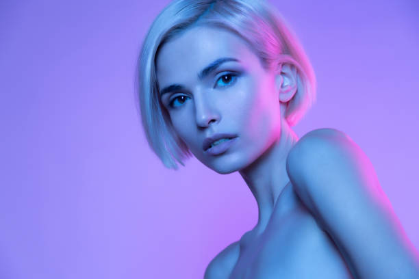 Beautiful  woman in neon nude portrait Beautiful european blond woman trendy glowing neon nude headshot art studio portrait. High fashion stylish image with attractive girl in colorful fashionable light. Perfect female young face human face light stock pictures, royalty-free photos & images