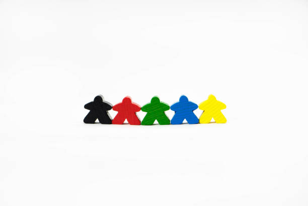 cinq hommes multicolores de jouet en bois se tiennent dans une rangée sur un fond blanc. le concept d’égalité, de tolérance et de paix mondiale. les parties de jeu de société meeples. - meeple photos et images de collection