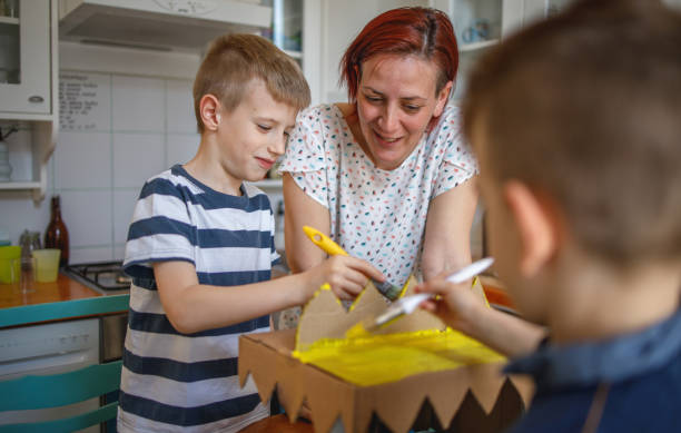 Brothers painting a cardboard dinosaur costume