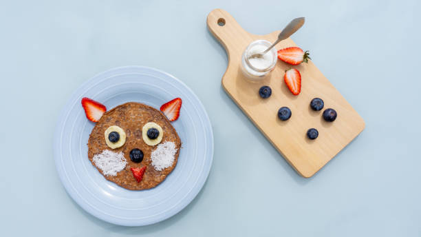 istock Creative cat pancake for kids in a plate isolated on blue background 1223640479