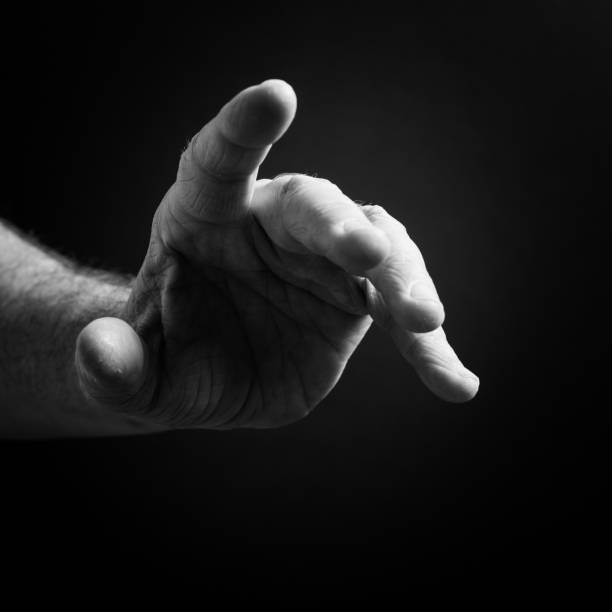 istock Black & white image of man`s hand pointing, isolated against a black background with dramatic sidelight 1223641769
