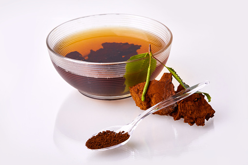 Human hand pouring hot tea into tea cup.