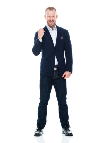 Full length of aged 30-39 years old with with beard caucasian young male business person standing in front of white background wearing smart casual who is excited and cheering and showing fist who is and doing fist pump