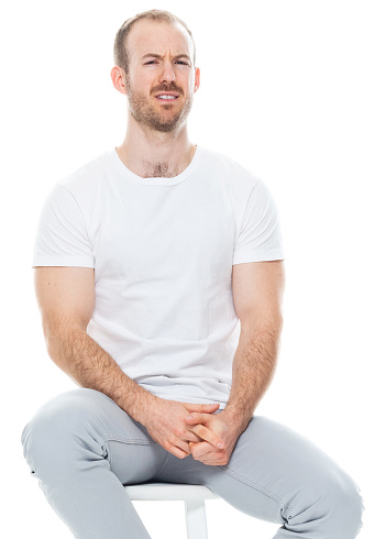 One person of aged 30-39 years old with with beard caucasian young male in front of white background wearing pants who is disgust