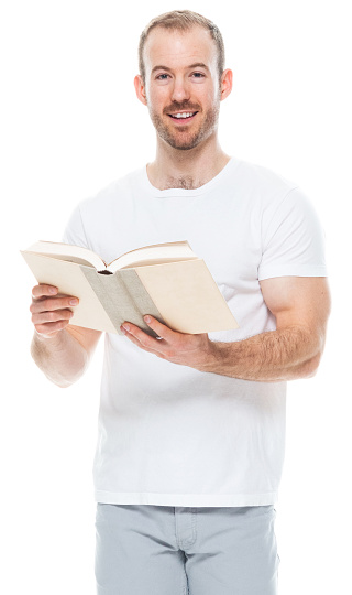 One person of aged 30-39 years old with with beard caucasian young male university student standing in front of white background wearing pants who is studying and holding textbook