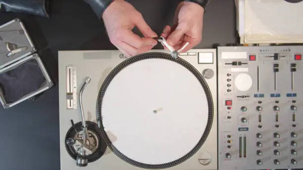 Photo of Sound engineer clean the turntable needle. Top view
