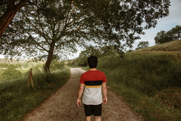 istock Rear view of young man walking in a path in a forest 1223650257