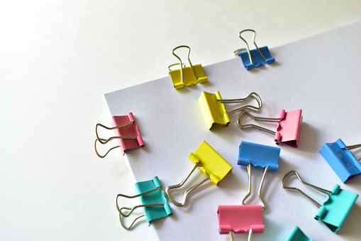 Metal colored stationery clips are attached to the Notepad and paper