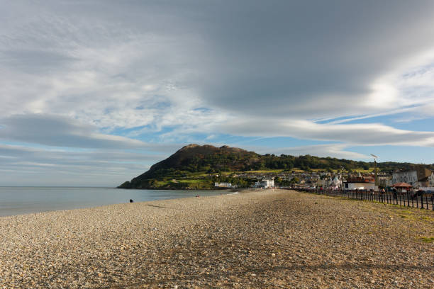 istock Beach with rocks and green hills and cloudy sky 1223654322