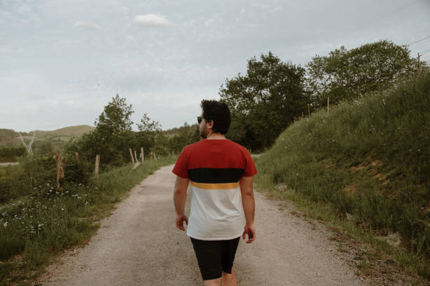 istock Rear view of young man walking in a path 1223655364