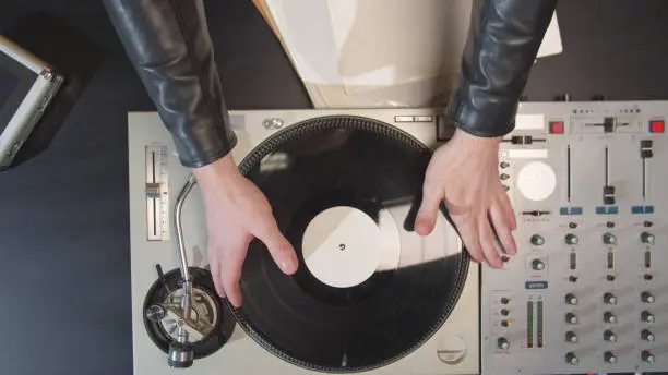 Photo of DJ unpacks a vinyl record and puts it on a turntable