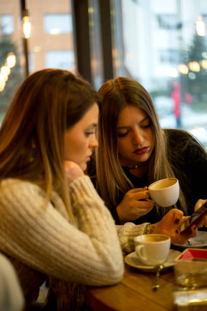 istock Two students having fun while sitting in college coffee shop and drinking coffee 1223663520