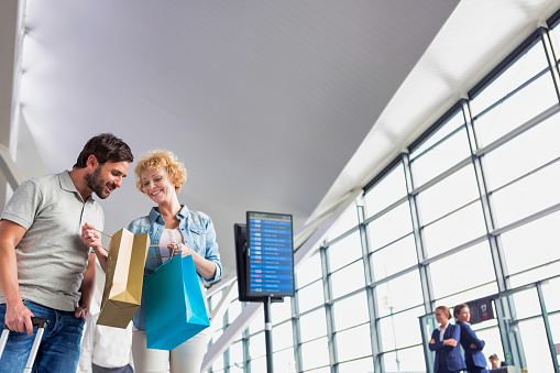 Portrait of mature woman showing present she bought in duty free with her husband at airport