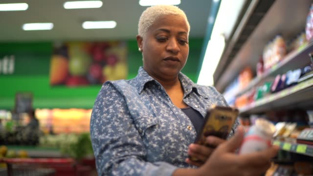 Woman buying at supermarket using mobile phone