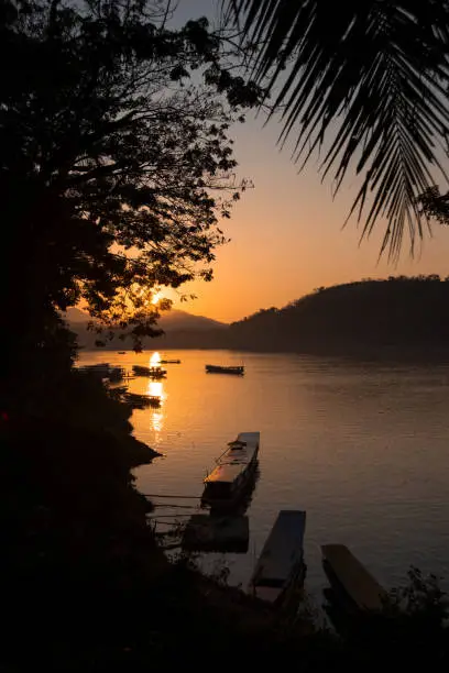 Photo of Sunset over the Mekong river with boats on the water in Luang Prabang, Laos.