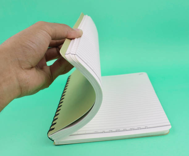 istock A person opening a white note paper diary placed on an isolated light blue paper background 1223669477