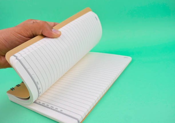 istock Person opening a white note paper diary placed on an isolated light blue paper background 1223670013