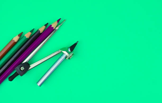 istock Silver color compass and three different color wood pencil crayons placed on top of a light blue paper background 1223670064