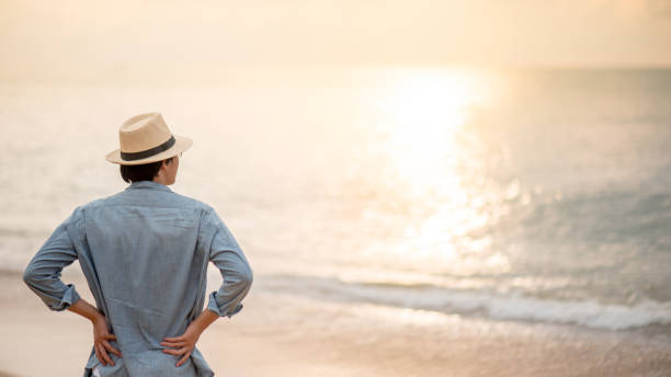 istock Asian man tourist standing on the beach looking at sunset 1223670425