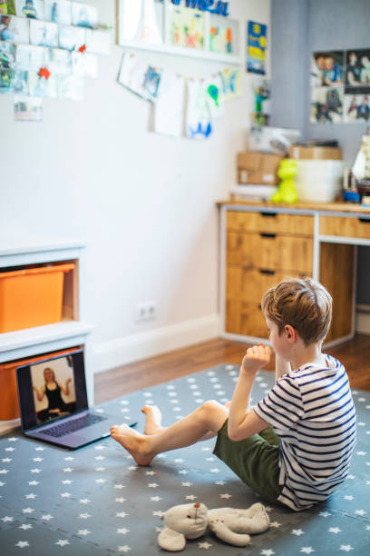 istock Little boy exercising at home with laptop during quarantine 1223670699