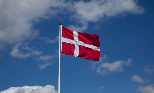 danish flag waving in the wind with blue sky and clouds - danish flag imagens e fotografias de stock