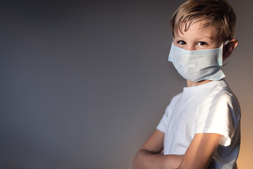 young boy wearing a mask with his arms crossed looking at camera confidently stock photo