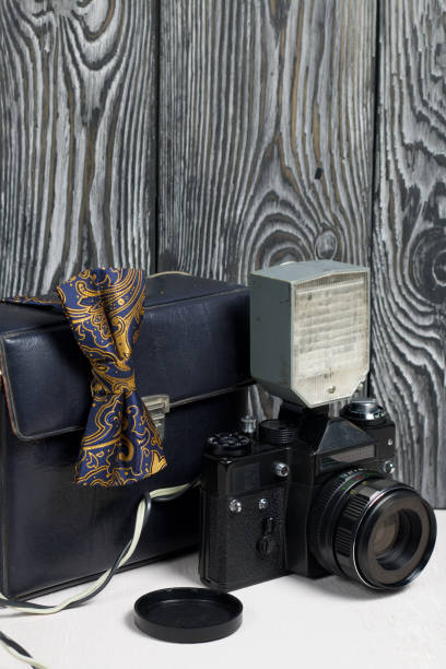 istock Photographer accessories. Camera and flash. There is a bow tie on the camera. Against the background of brushed pine boards. 1223679574