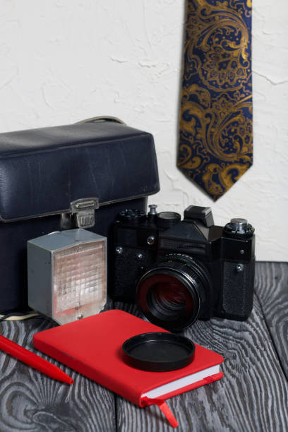 istock Photographer accessories. Camera, flash, tie, notebook and pen. On brushed pine boards. 1223679580