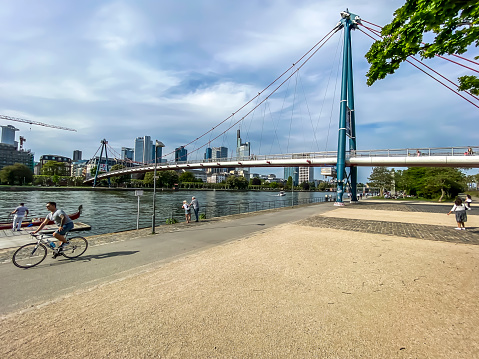 Frankfurt, Germany - 08th May 2020: A german photographer visiting the city, taking pictures of the promenade at the river Main with the Holbeinsteg pedestrian bridge and the skyline in the background.