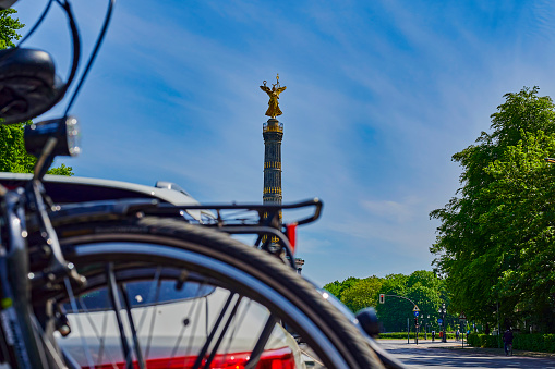 Berlin, Germany - May 8, 2020: Unfocussed parked car with a bike carrier attached to the stern and bicycles mounted on it. In the background you see the Berlin Siegessaeule, a historic landmark.